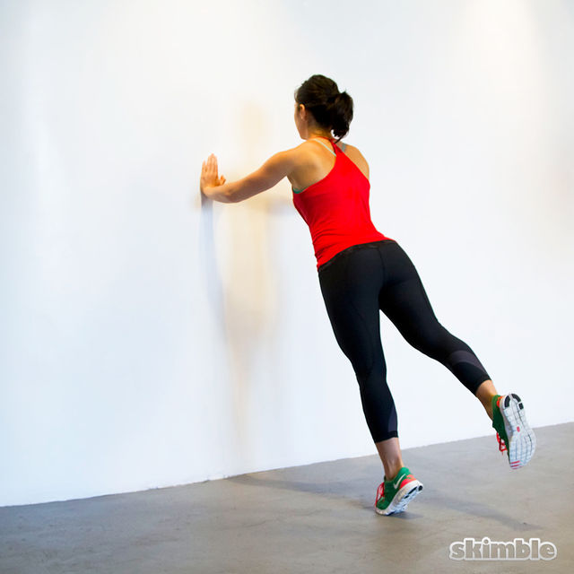 Chica haciendo flexiones en pared.